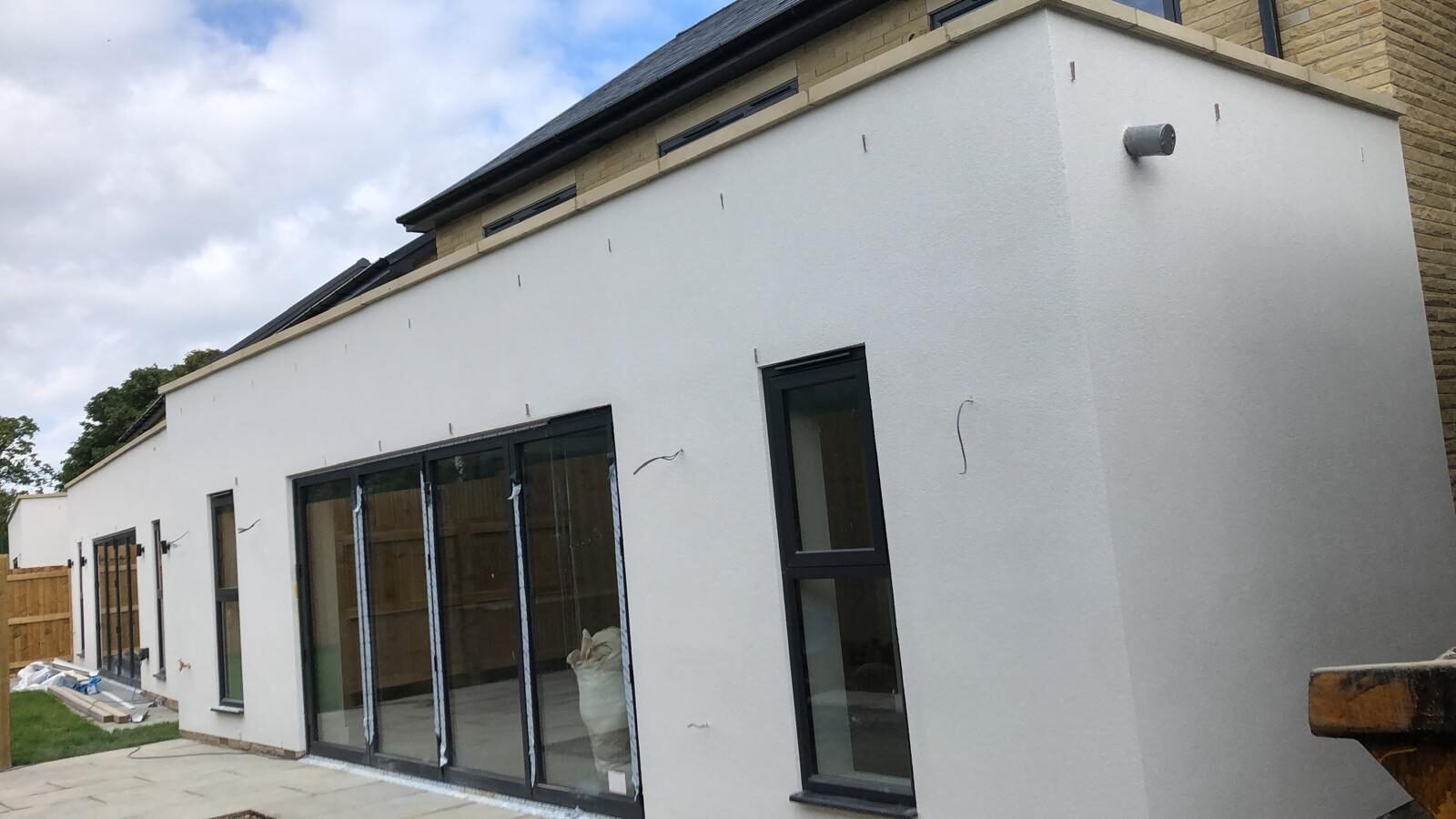 White silicone rendered bungalow with grey bifold doors, rear elevation