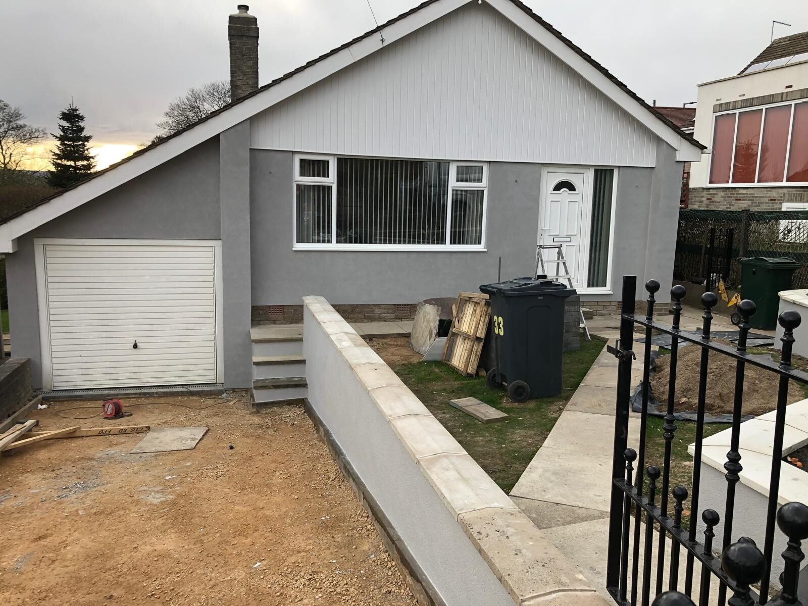 Grey silicone rendered detached bungalow with garage and retaining wall