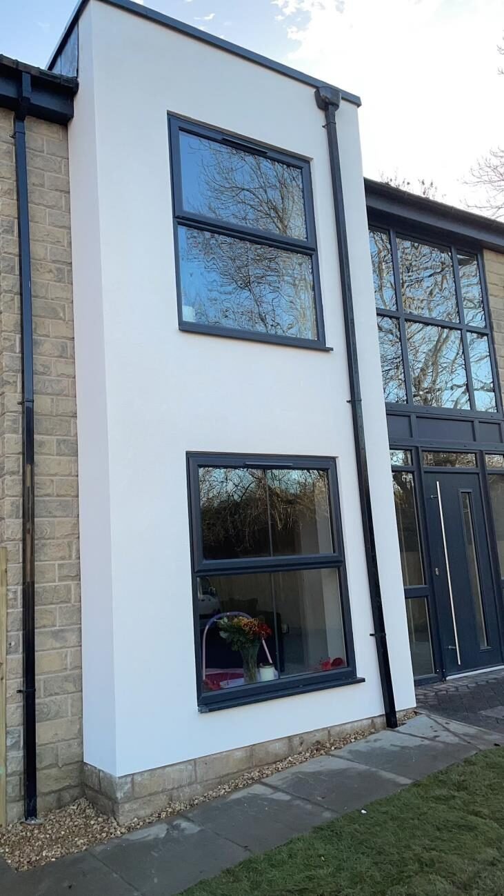 White rendered two-storey home with glazed gable and dark windows